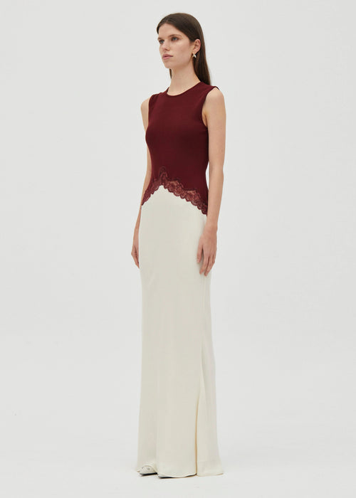 Woman wearing a crimson top and white bottom dress  on grey  background