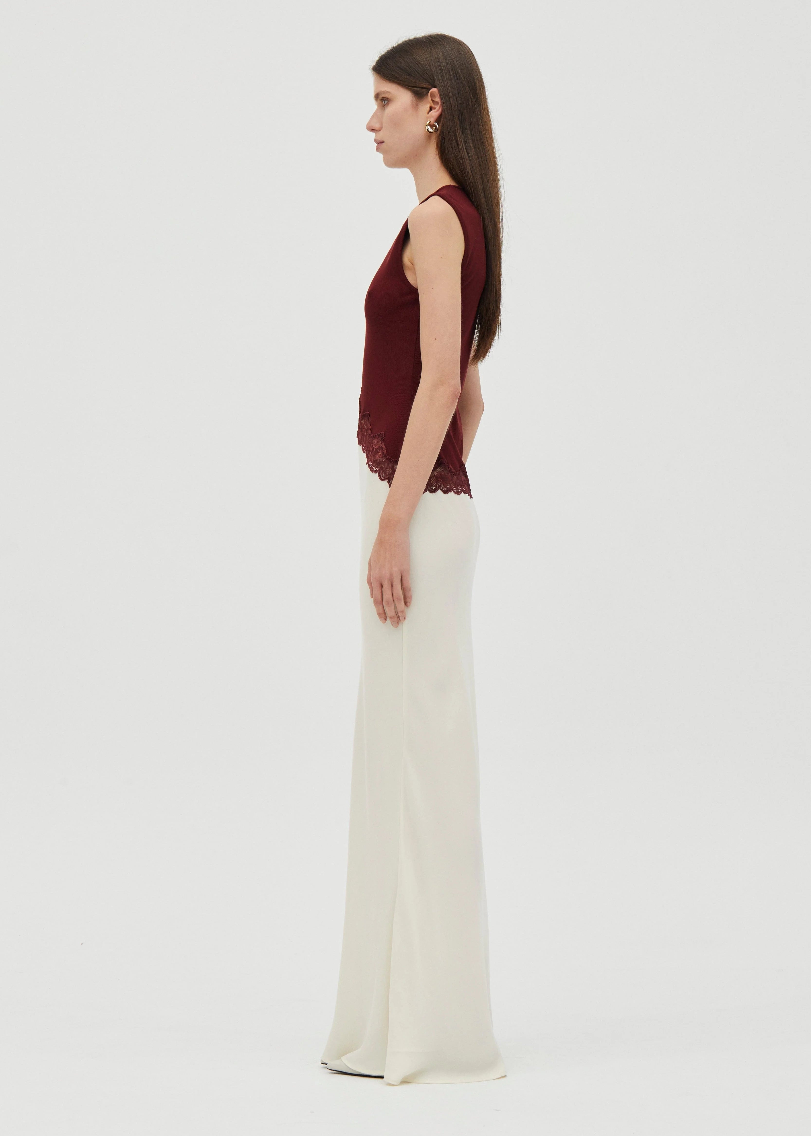 Woman wearing a crimson top and white bottom dress  on grey  background