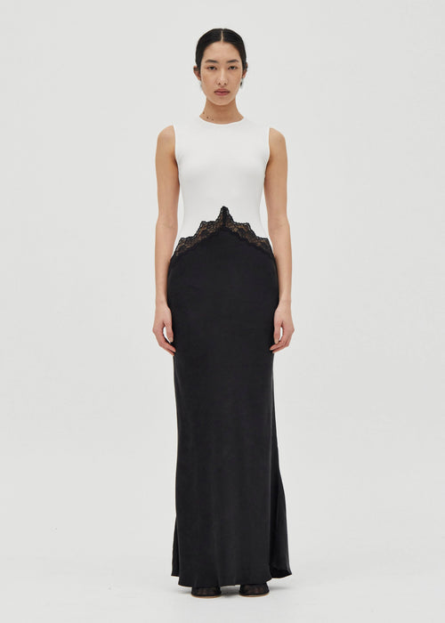 Woman wearing a white sleeveless top and black long skirt dress on a white background


