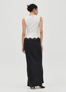 Woman wearing a white sleeveless top and black long skirt dress on a white background