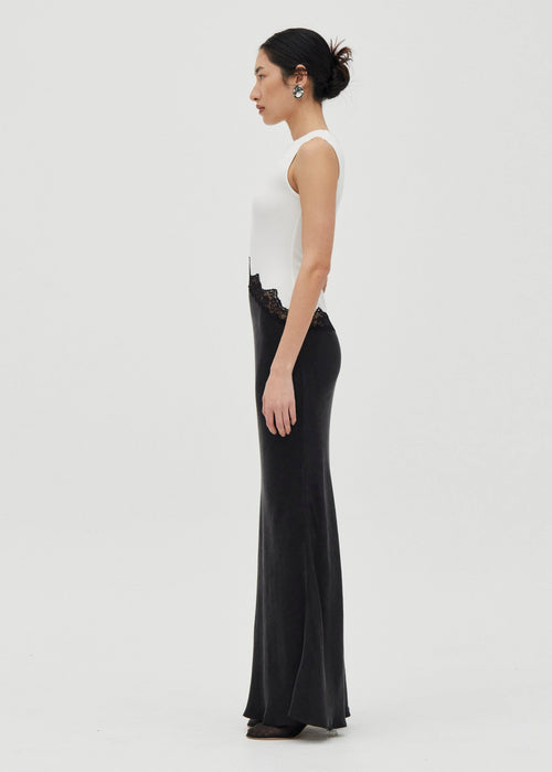 Woman wearing a white sleeveless top and black long skirt dress on a white background