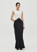 Woman wearing a white sleeveless top and black long skirt dress on a white background