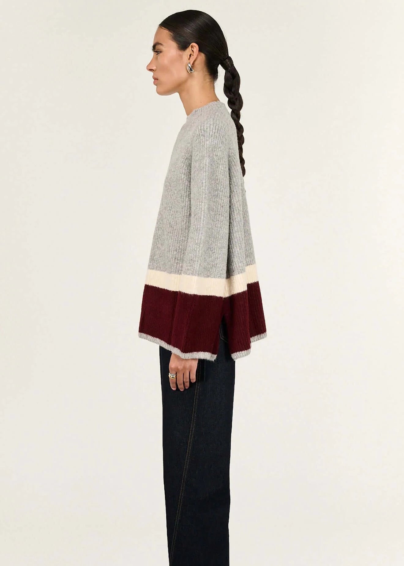 Woman wearing a grey sweater with a colour-blocked design on a white background