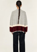 Woman wearing a grey sweater with a colour-blocked design on a white background