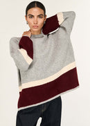 Woman wearing a grey sweater with a colour-blocked design on a white background