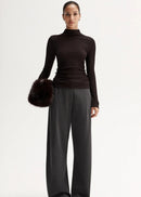 Woman wearing a black turtleneck and gray pants on a white background