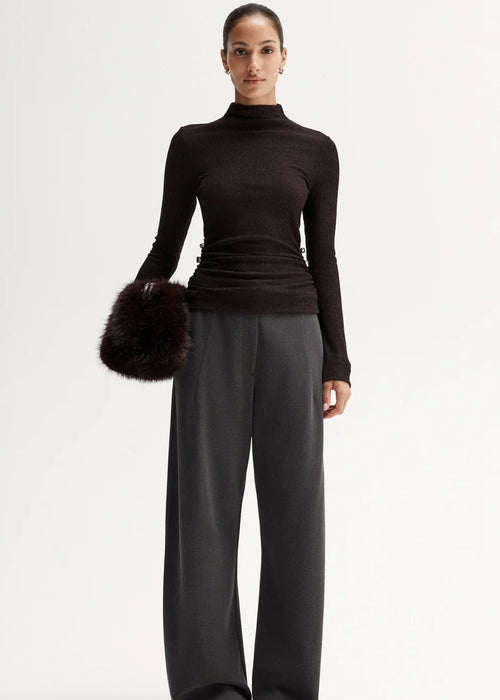 Woman wearing a black turtleneck and gray pants on a white background