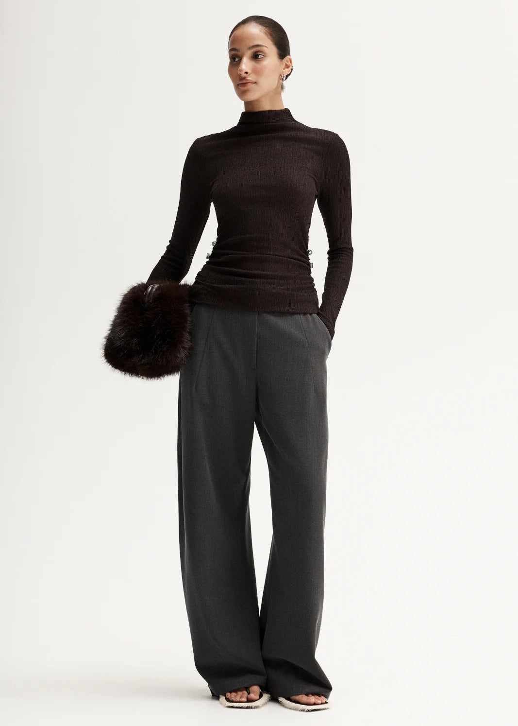 Woman wearing a black turtleneck and grey pants on a white background
