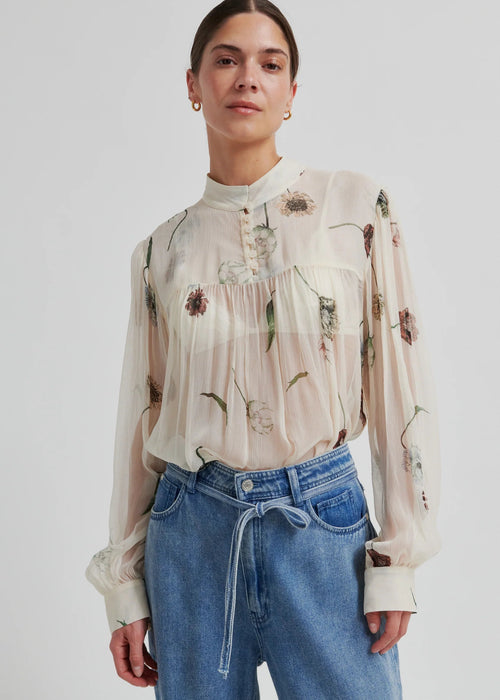 Woman wearing a floral blouse and blue jeans on a white background