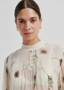 Woman wearing a floral blouse and blue jeans on a white background