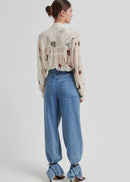 Woman wearing a floral blouse and blue jeans on a white background
