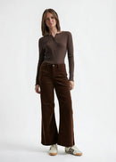 Woman wearing a brown long-sleeve top and brown velvet  pants on a white background