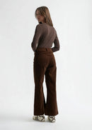 Woman wearing a brown long-sleeve top and brown velvet  pants on a white background