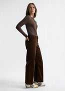 Woman wearing a brown long-sleeve top and brown velvet  pants on a white background