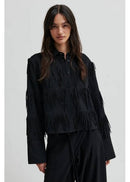 Woman wearing a black fringed shirt against a white background