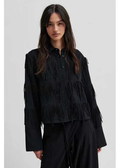 Woman wearing a black fringed shirt against a white background
