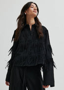 Woman wearing a black fringed shirt against a white background