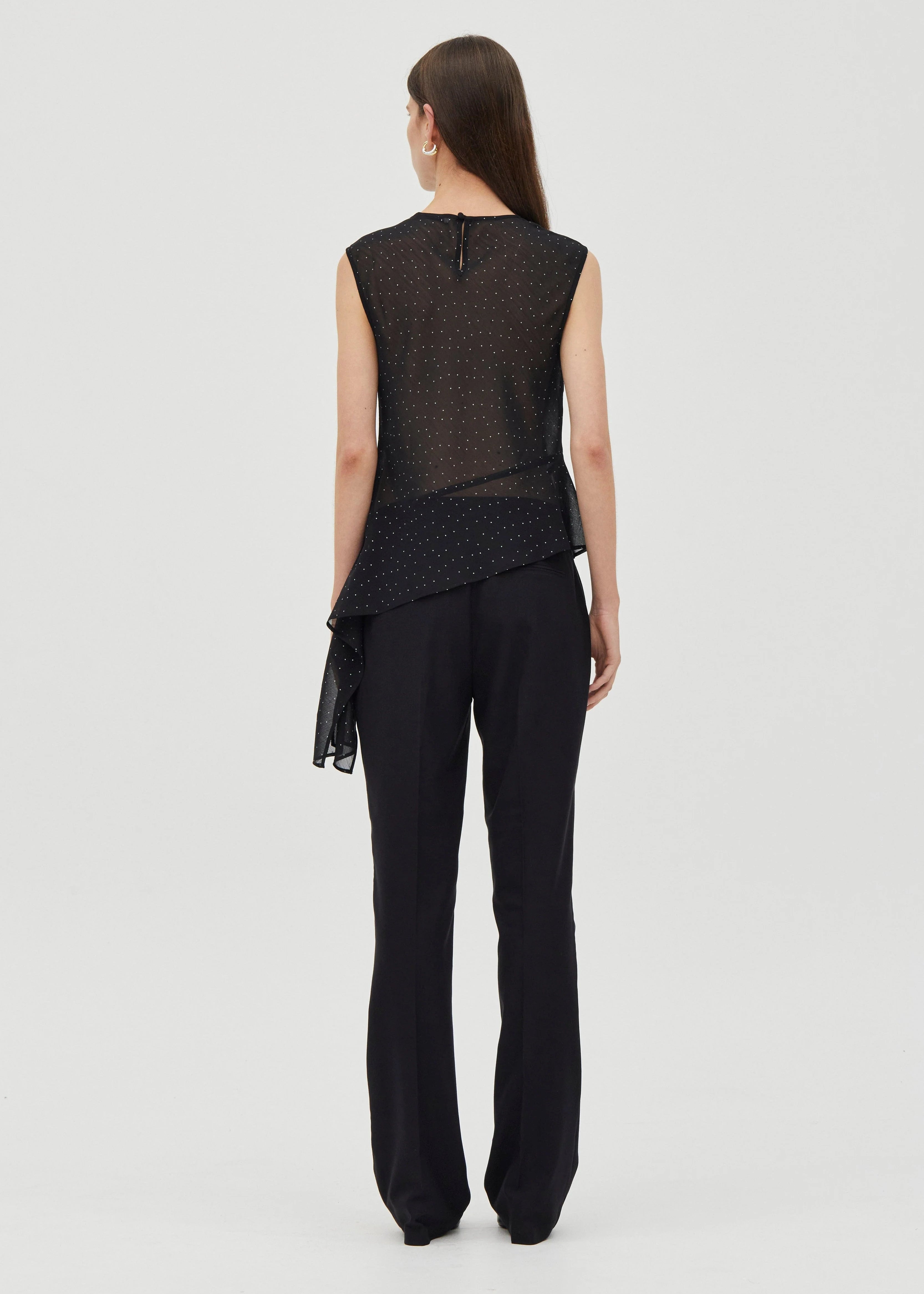 Woman wearing a black sleeveless top and black pants on a white background