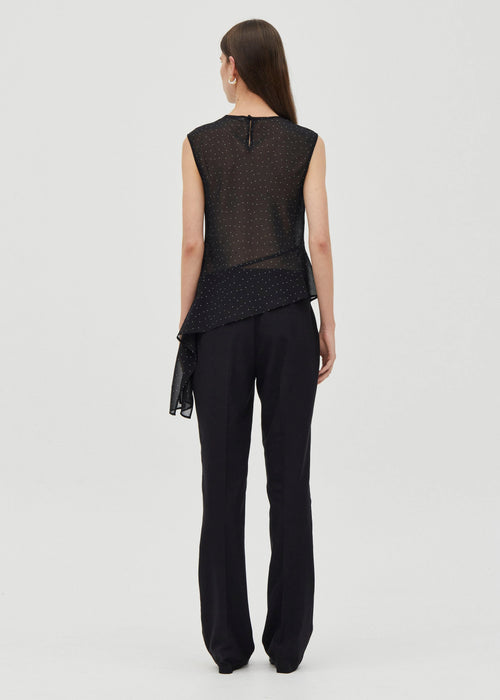 Woman wearing a black sleeveless top and black pants on a white background