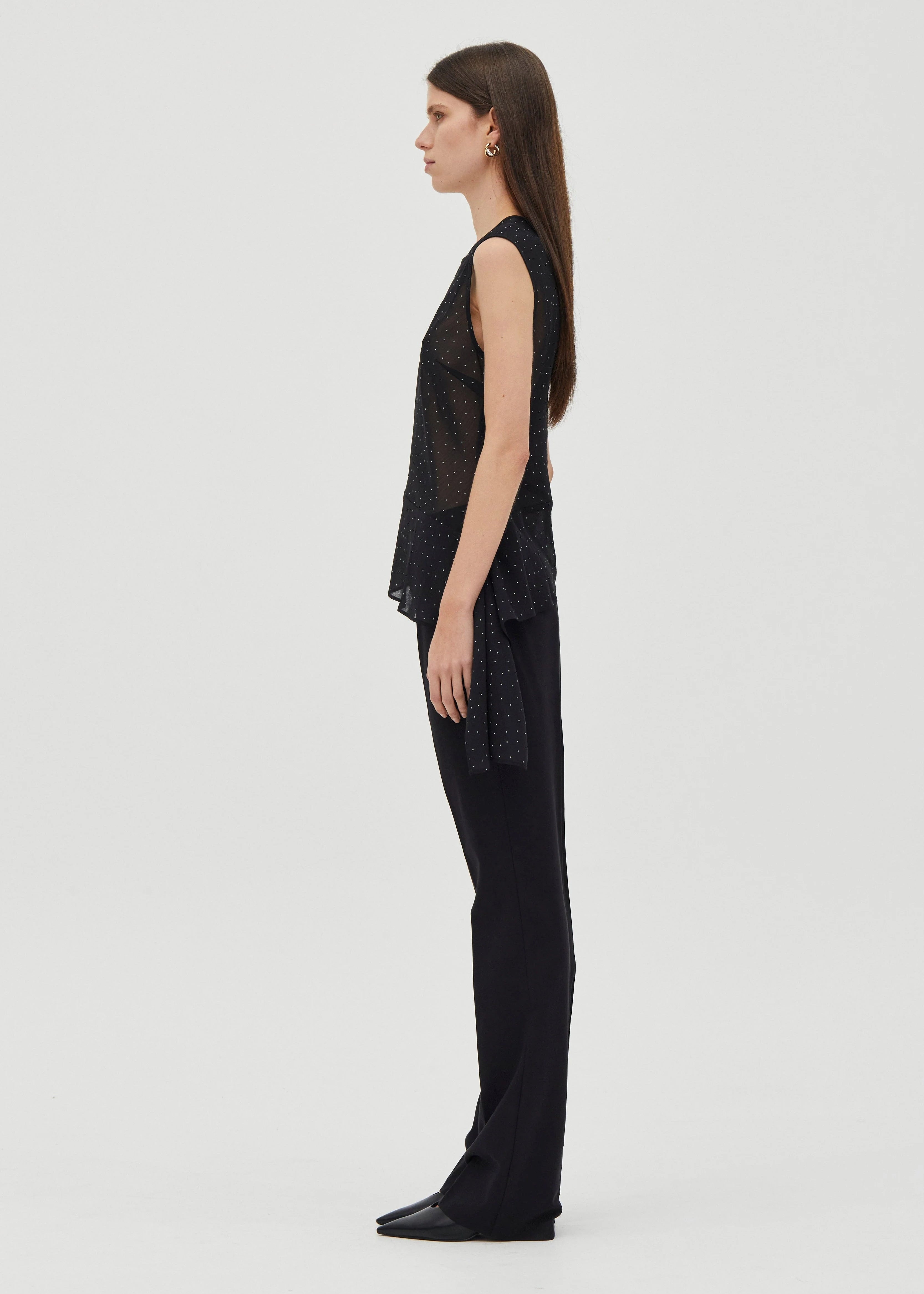 Woman wearing a black sleeveless top and pants on a white background