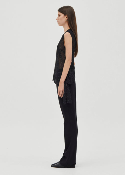 Woman wearing a black sleeveless top and pants on a white background