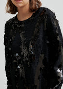 Woman wearing a black sequin dress with knee-high boots on a white background