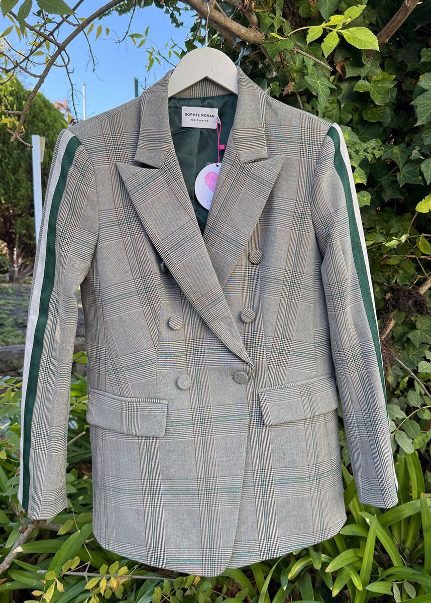 Plaid blazer on a hanger against a natural background