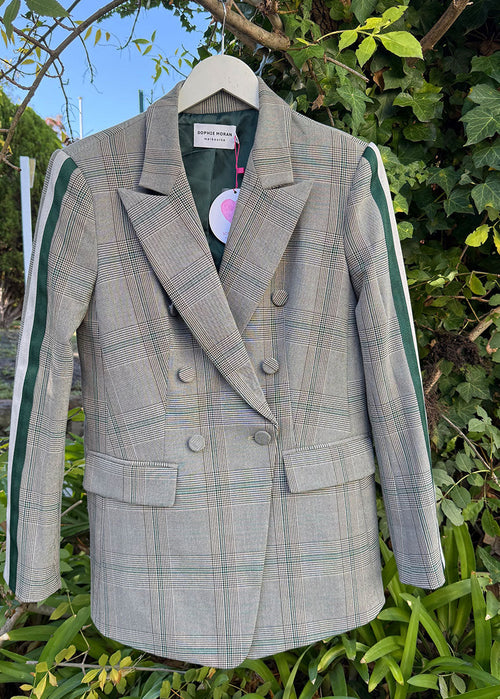 Plaid blazer on a hanger against a natural background