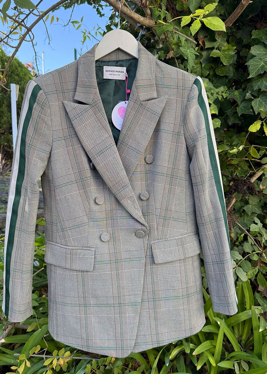 Plaid blazer on a hanger against a natural background