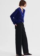 Woman wearing a blue cardigan and black pants on a white background