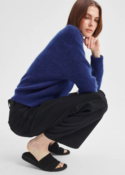 Woman wearing a blue cardigan and black pants on a white background