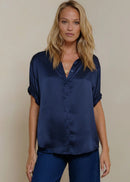 Woman wearing a navy blue shirt and pants against a beige background