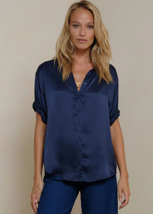 Woman wearing a navy blue shirt and pants against a beige background