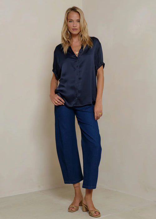Woman wearing a navy blue shirt and pants against a beige background