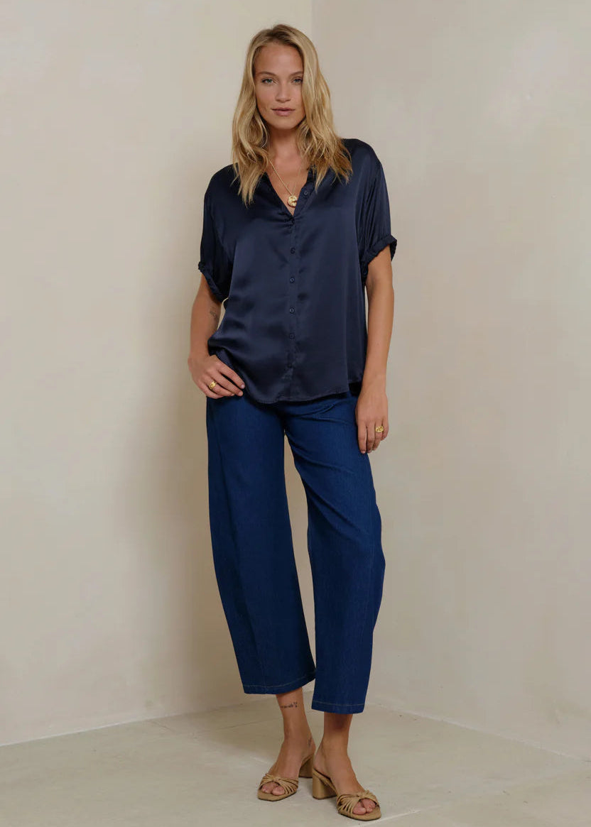 Woman wearing a navy blue shirt and pants against a beige background
