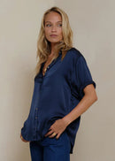Woman wearing a navy blue shirt and pants against a beige background