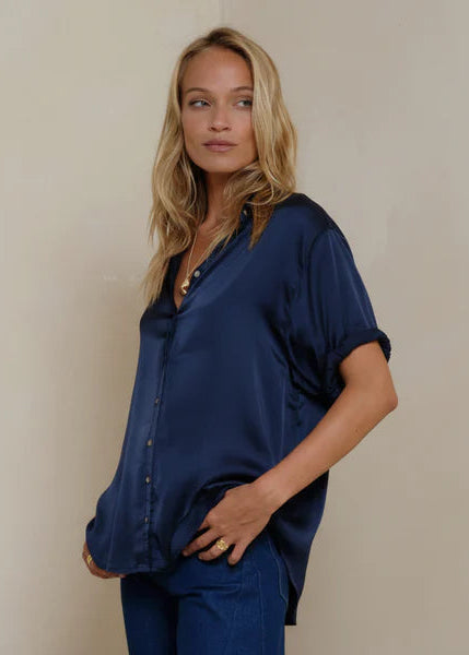 Woman wearing a navy blue shirt and pants against a beige background