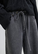 Woman wearing a dark grey wide-leg jeans on a light grey background