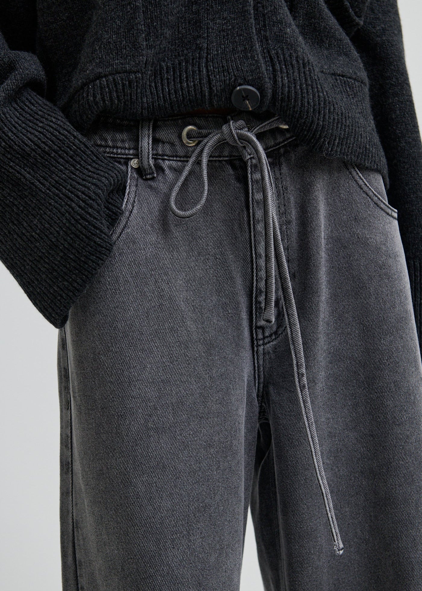 Woman wearing a dark grey wide-leg jeans on a light grey background