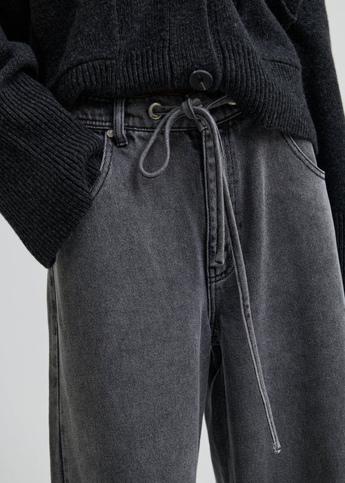 Woman wearing a dark grey wide-leg jeans on a light grey background