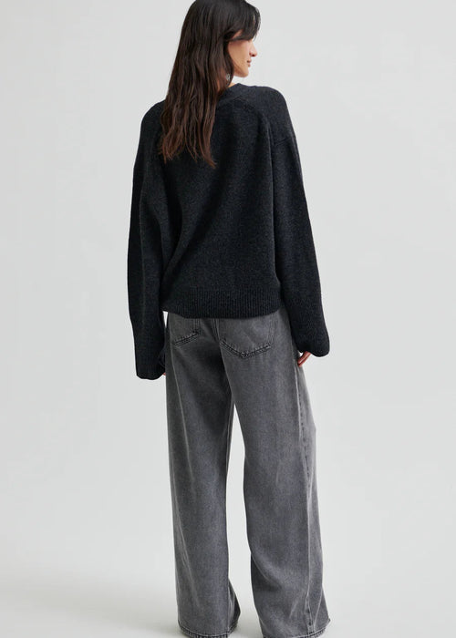 Woman wearing a dark grey wide-leg jeans on a light grey background