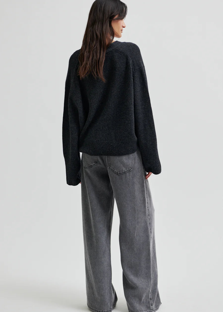 Woman wearing a dark grey wide-leg jeans on a light grey background