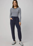 Woman wearing a striped long-sleeve top and navy jogger pants on a grey background