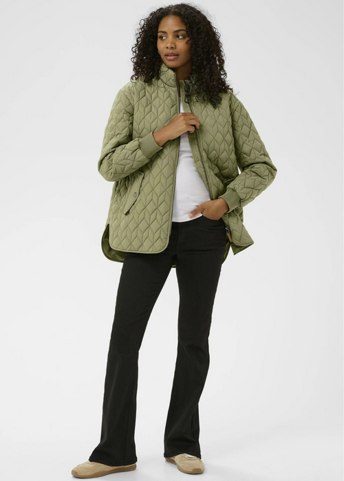Woman wearing a green quilted jacket on a white background