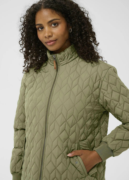 Woman wearing a green quilted jacket on a white background