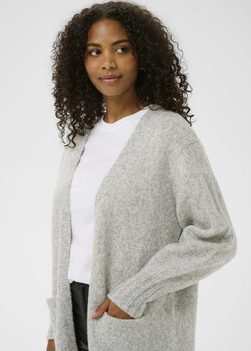 Woman wearing a light grey cardigan over a white shirt on a white background