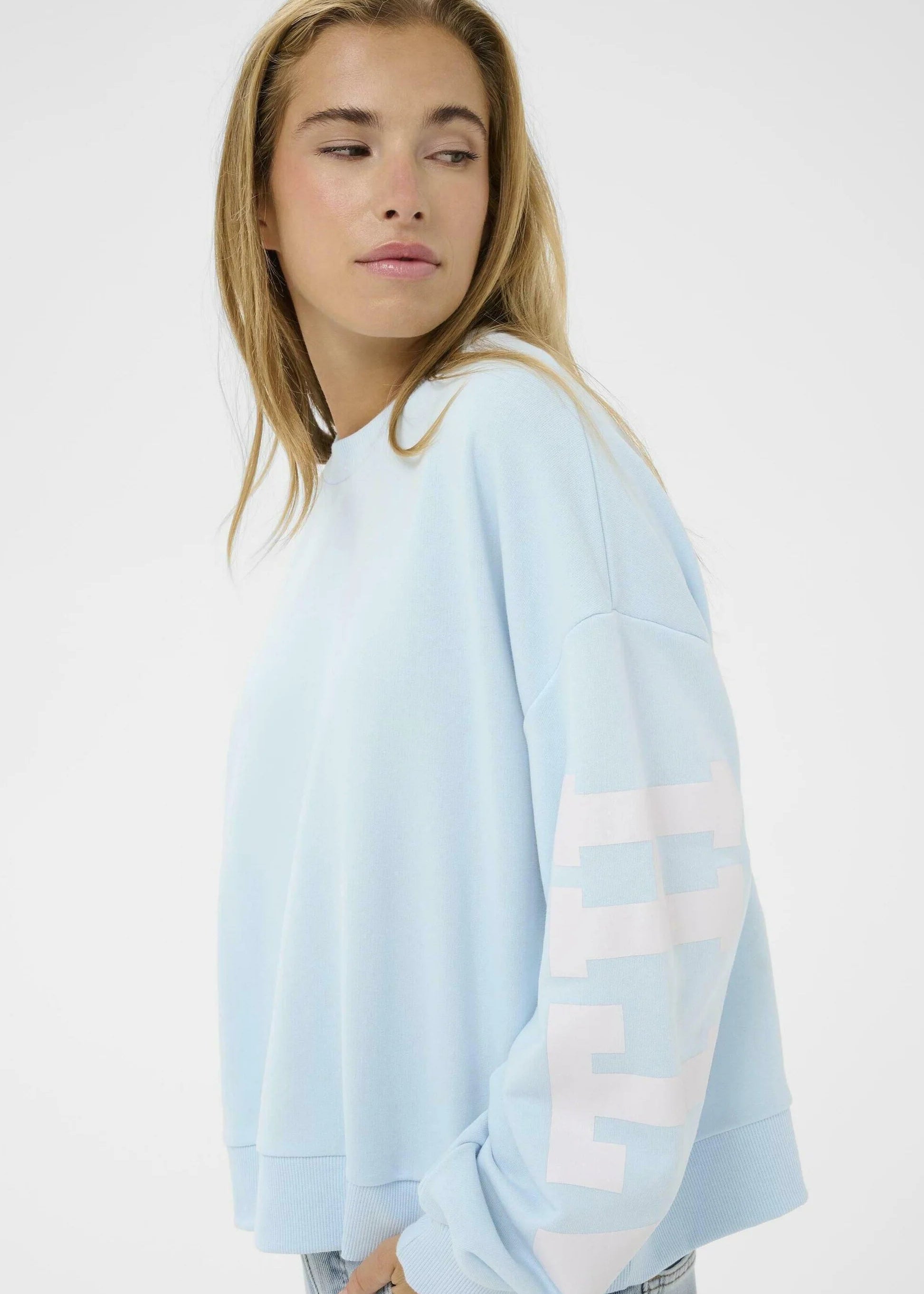 Person wearing a light blue sweatshirt and jeans on a white background