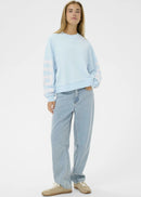 Person wearing a light blue sweatshirt and jeans on a white background
