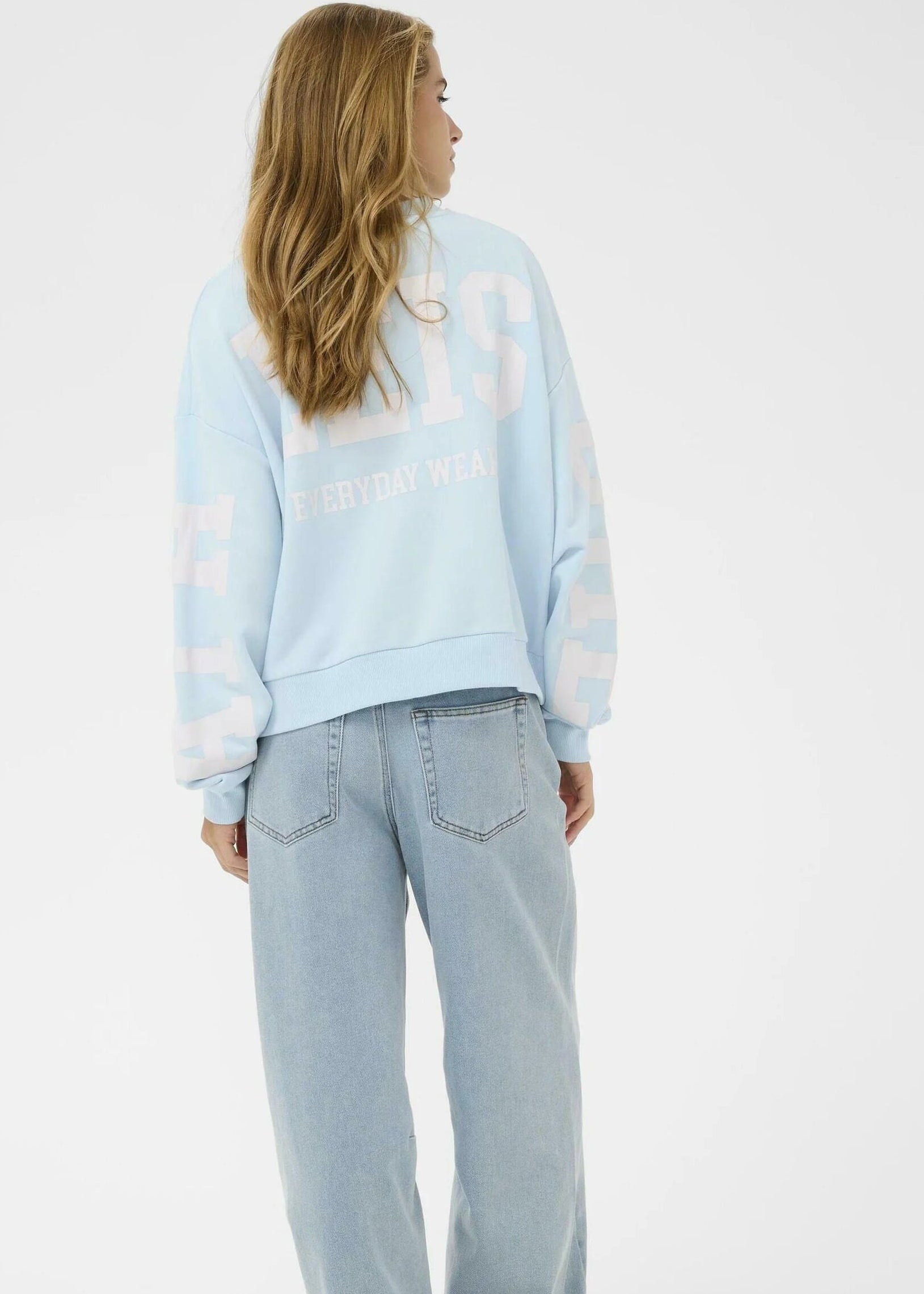 Person wearing a light blue sweatshirt and jeans on a white background