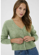Woman wearing a green cardigan and blue jeans on a white background